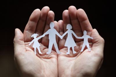 Pair of hands holding a paper family of daughter, father, mother, son